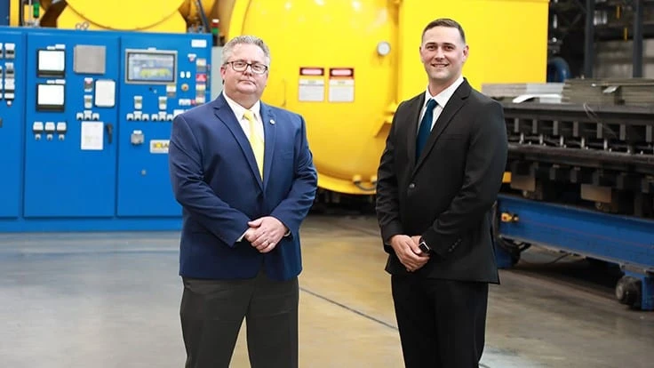 Mike Johnson, sales director, with Zachary Thomas (right) in front of the 48ft vacuum furnace.