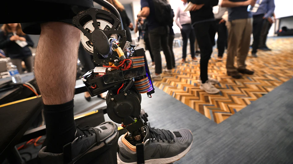 Andrew Seelhoff, left, a first-year PhD student in mechanical engineering at the University of Michigan, demonstrates the robotic prosthetic designed by Robert Gregg’s Locomotor Control Systems Laboratory, at IROS 2023 in October.